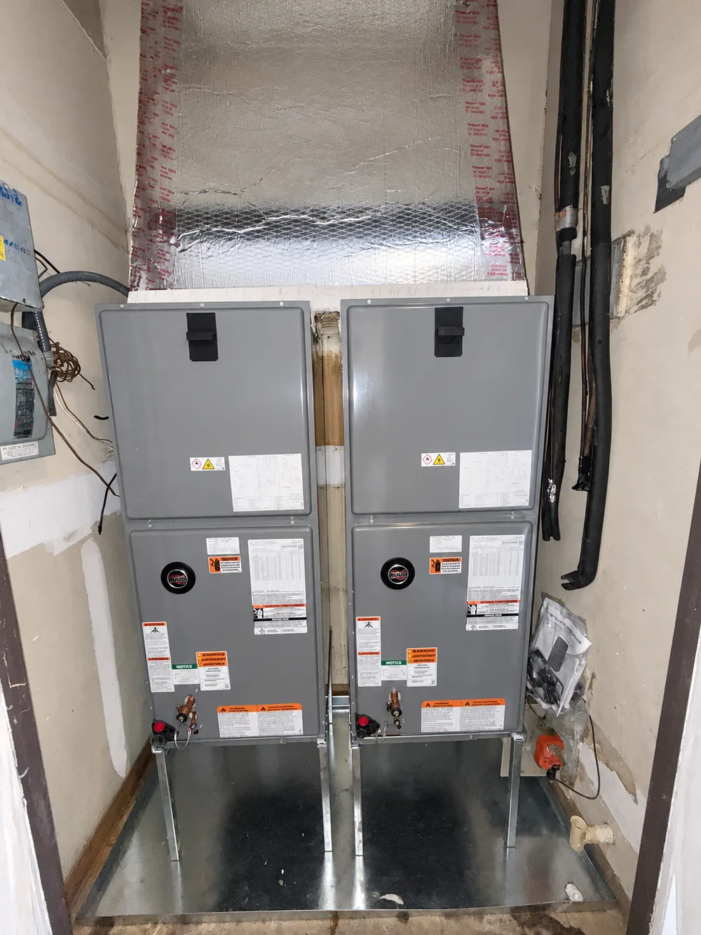 Two RUUD air handlers with foil-covered ductwork above