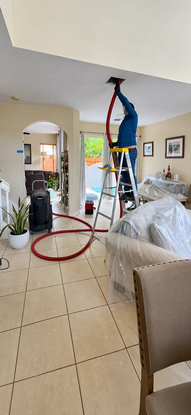 Duct cleaning in a living room with furniture covered by protective sheets