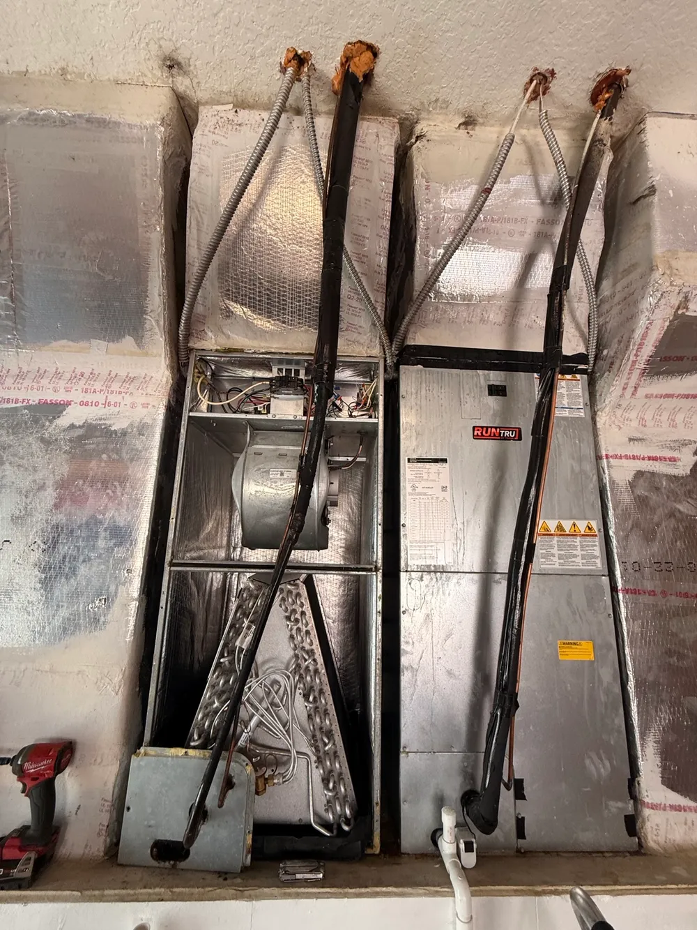 Open air handler showing the evaporator coil, blower and cabinet beside another unit