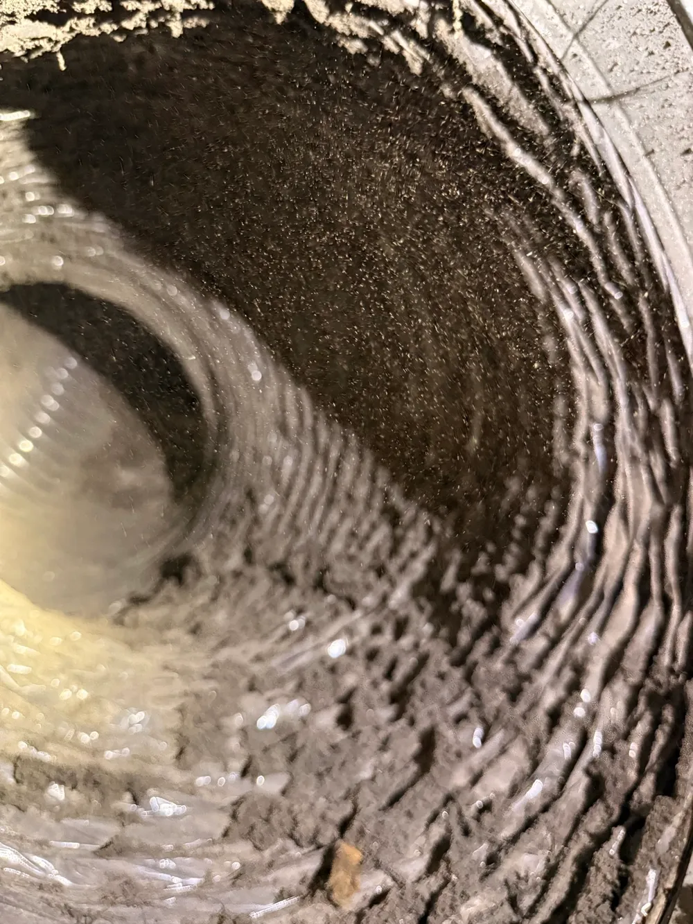 Flexible air duct interior with visible dust and buildup before cleaning